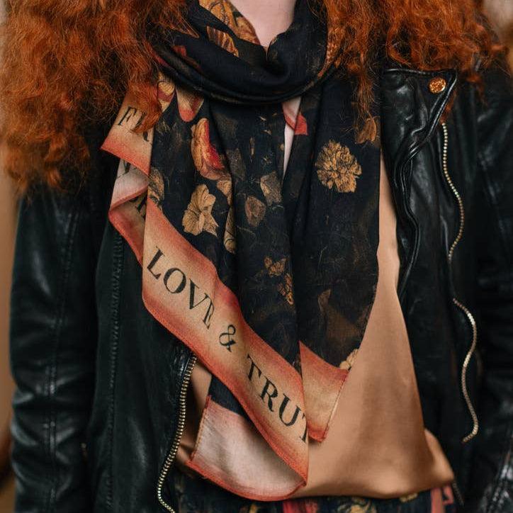 Black floral scarf with 'Love & Truth' text, worn with leather jacket, heart-themed gift