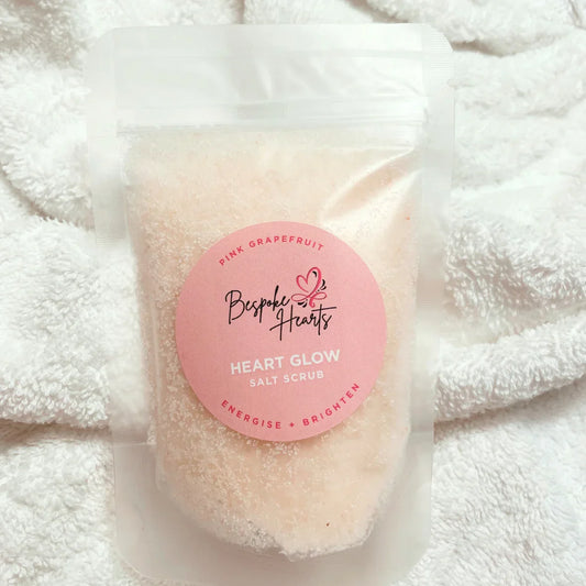Pink Grapefruit Heart Glow Salt Scrub in clear pouch on white towel, energising & brightening bath product