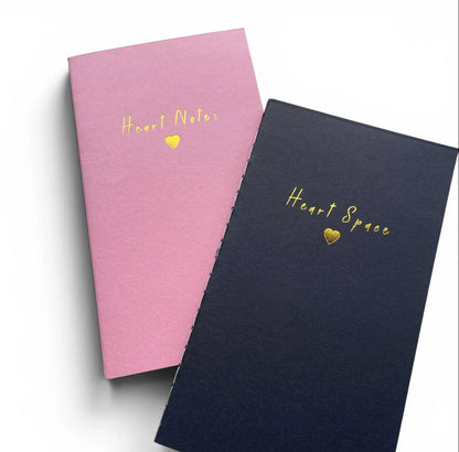 Pink and navy notebooks with gold 'Heart Notes' and 'Heart Space' text and heart symbols