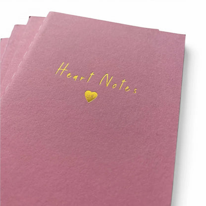 Pink notebook with gold 'Heart Notes' text and heart symbol, ideal for romantic gifts