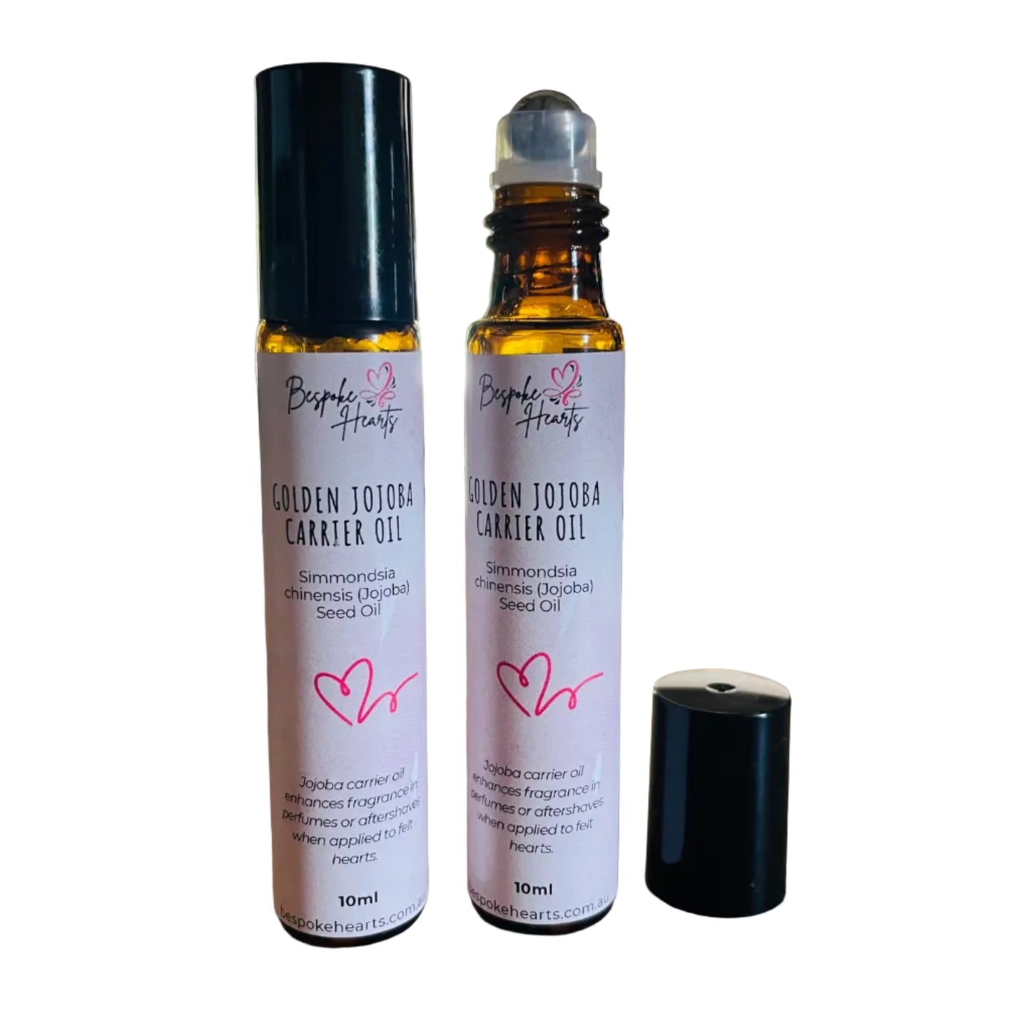 Two bottles of Golden Jojoba Carrier Oil on a wooden surface with a blurred indoor background.