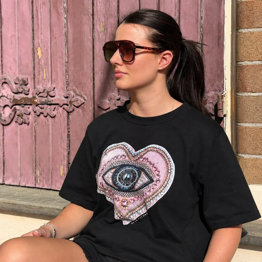 Woman wearing a black Bespoke Hearts The Lover's Eye Tee featuring a jeweled heart and eye design.