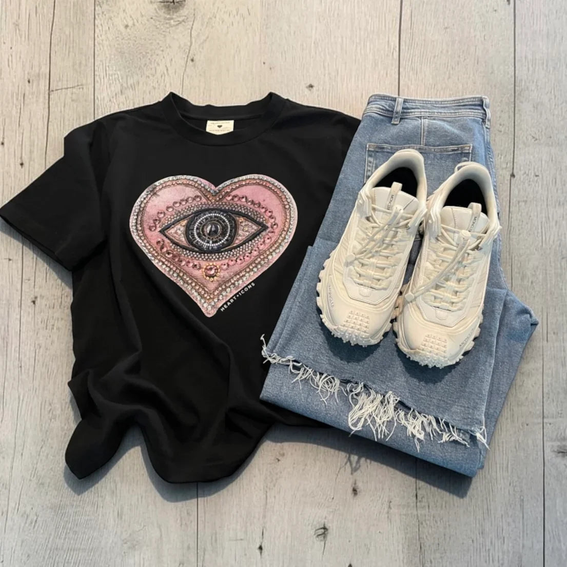 Flat lay image of light jeans, black tee and white runners