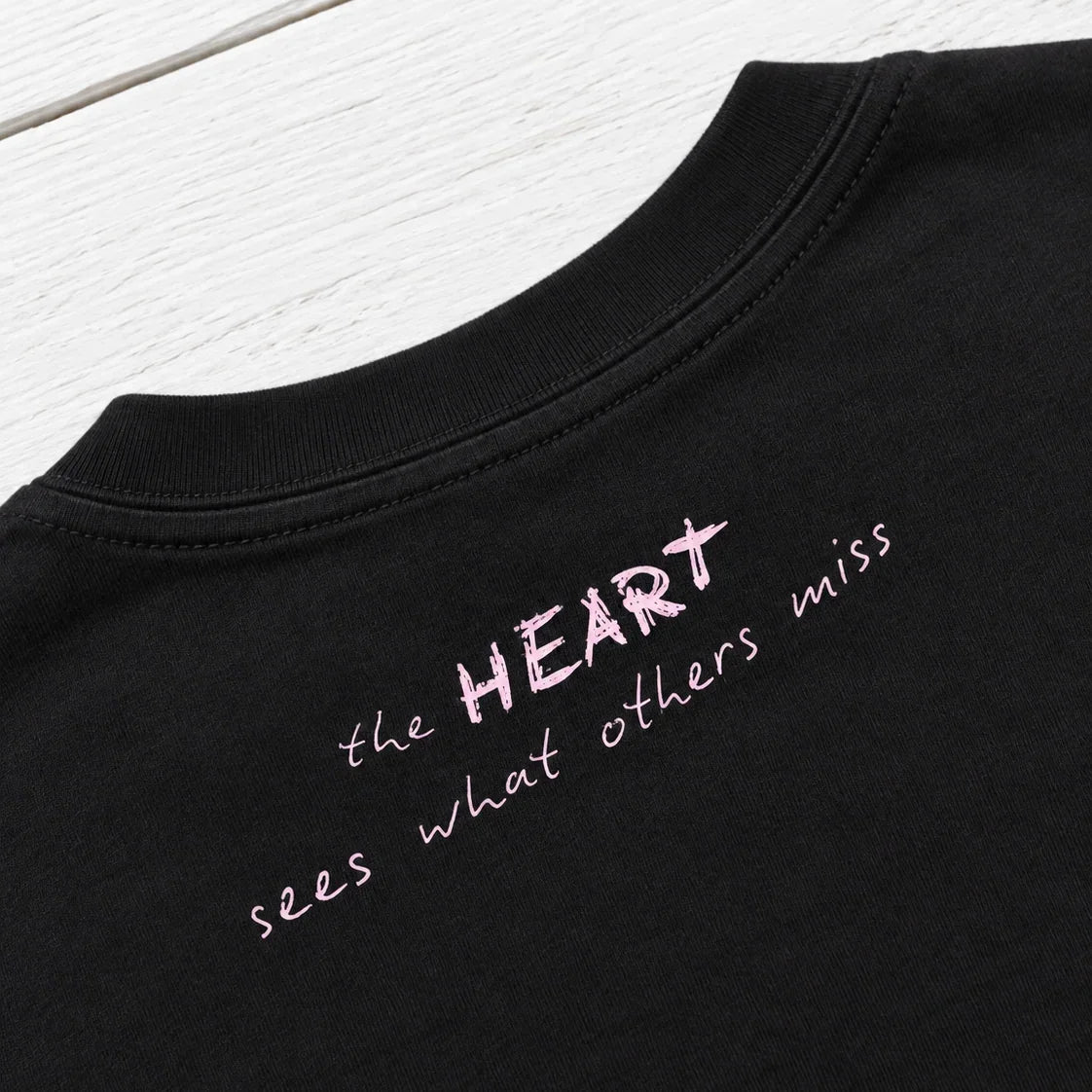 Close-up of Bespoke Hearts black tee with pink text 'the HEART sees what others miss'
