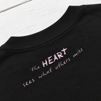 Close-up of Bespoke Hearts black tee with pink text 'the HEART sees what others miss'